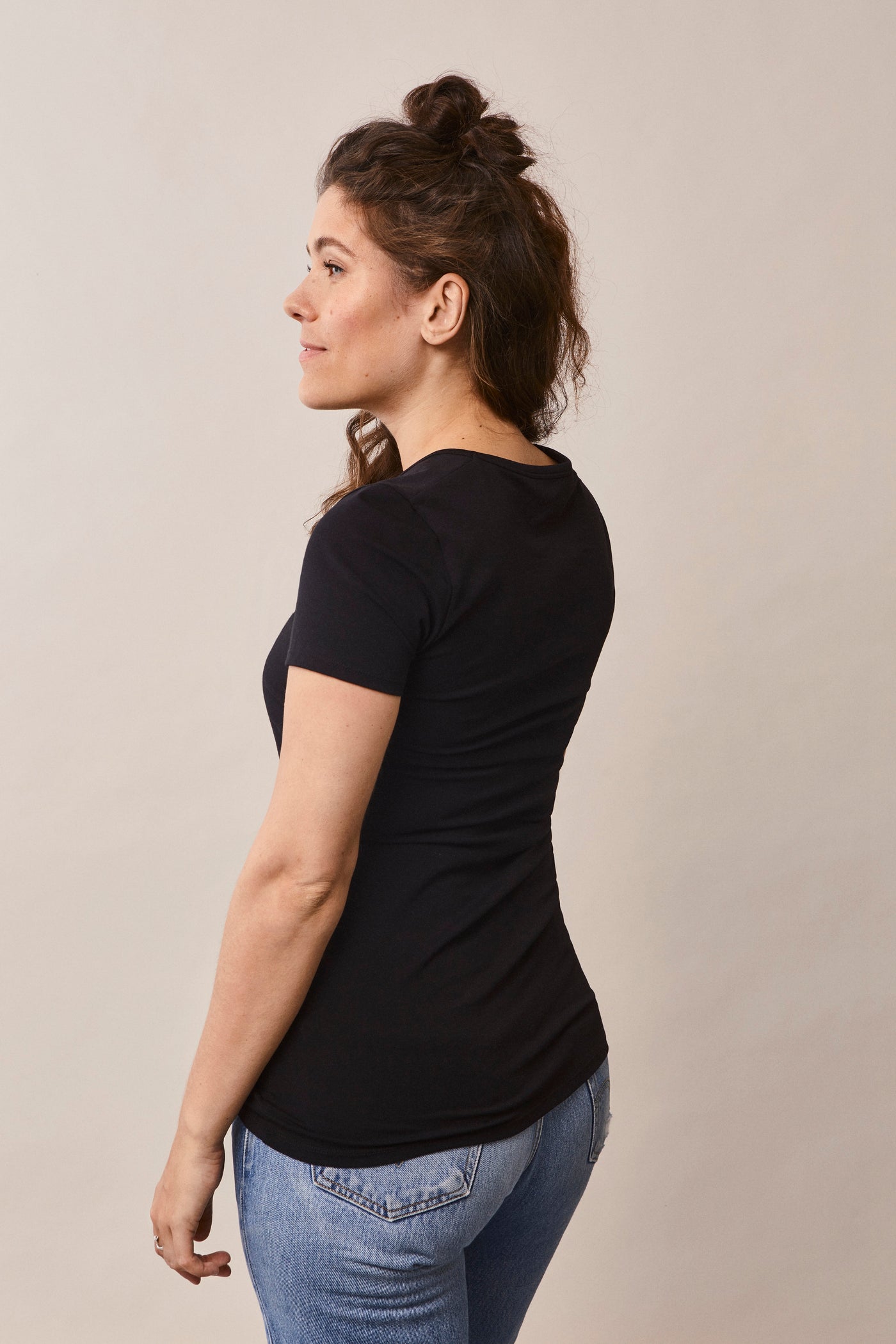 Femme de 3/4 portant le t-shirt Le Classique manches courtes de grossesse et d'allaitement en coton bio certifié GOTS, coloris noir.